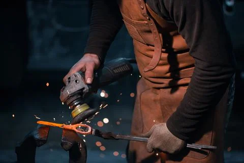 Blacksmith removes scale from red-hot metal. Фото