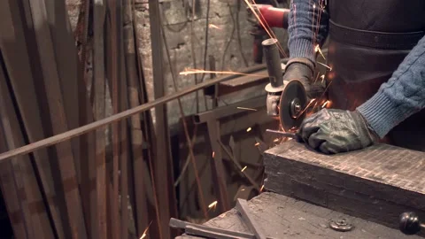 Blacksmith sawing  iron piece in workshop Stock Footage 132653232