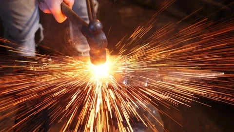 Blacksmith shaping a hot piece of metal on the anvil. Sparks in slow motion. Stock Footage 219957130
