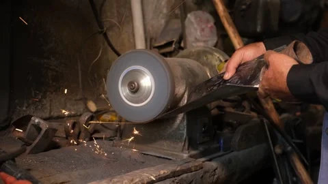 Blacksmith Sharpening Axe In Workshop With Grinder Sparks, August 20,2021, Stock Footage 324566928