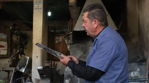 Blacksmith Sharpening Axe In Workshop With Grinder Sparks, August 20,2021, Stock Footage 324567049