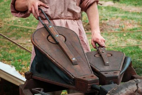 Blacksmith squeezing bellows to kindle fire Stock Photos