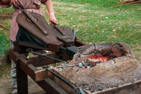Blacksmith squeezing bellows to kindle fire Stock Photos
