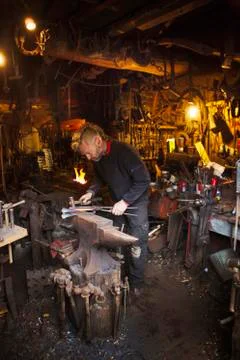 Blacksmith standing at an anvil in his workshop Stock Photos