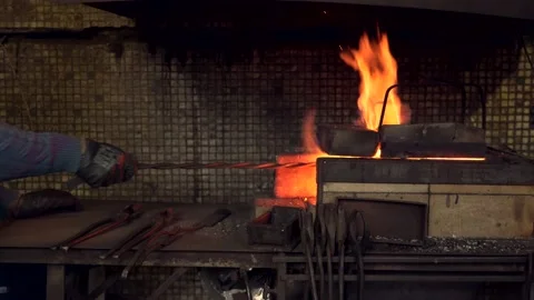 Blacksmith stirring coals in burning fire by metal poker Stock Footage 132652865