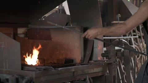 Blacksmith stoking the fire of his forge in his workshop. Stock Footage 253848042