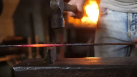 Blacksmith striking and breaking red hot metal rod with hammer on anvil. Stock Footage 219957085