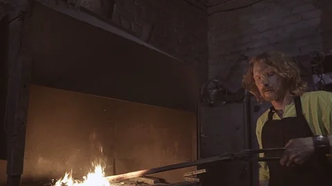 The blacksmith takes the workpiece out of the oven and processes a large hammer Stock Footage 108956888