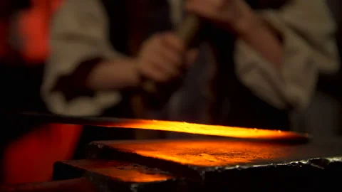 Blacksmith teaches a boy working with a hammer forging metal sword Stock Footage 120004623