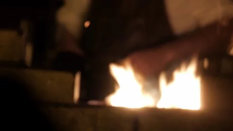 Blacksmith Tending Forge with Fire and Sparks in Dimly Lit Workshop Close Up Video stock 339239534