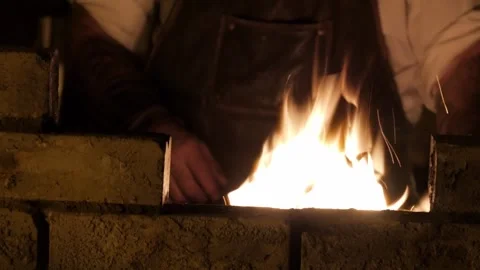 Blacksmith Tending Forge Fire with Sparks in Workshop at Night, Close Up Video stock 339240381