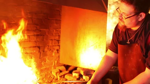 Blacksmith tends raging fire in his forge, slow motion, medium shot Stock Footage 39017477