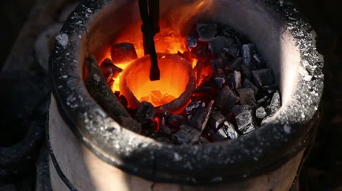Blacksmith tongs pulls a red-hot crucible with the metal from the hearth Stock Footage 54688545