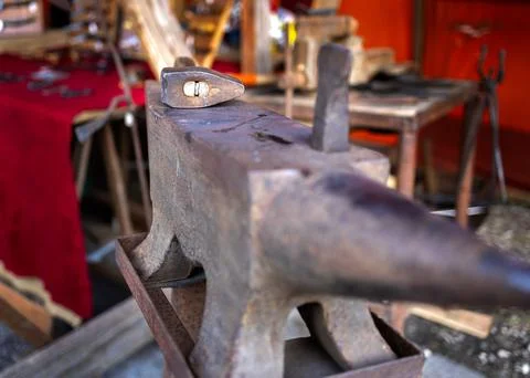 Blacksmith tools set with heavy iron anvil hammer and tongs on workbench Stock Photos