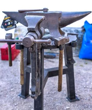 Blacksmith tools set with heavy iron anvil hammer and tongs on workbench Stock Photos