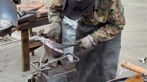 Blacksmith uses a hammer to forge metal A male blacksmith forges hot metal with Stock Footage 268736643