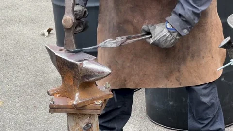 Blacksmith uses a hammer to forge metal A male blacksmith forges hot metal with Stock Footage 269823239
