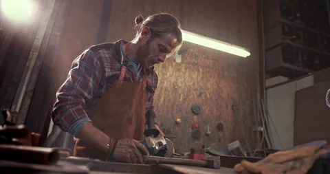 Blacksmith using power tools and working on metal in workshop Stock Footage 90033747