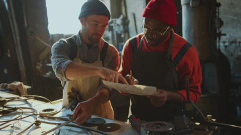 Blacksmith Using Roll Meter as Apprentice Writing Measurements in Workshop Stock Footage 274391380