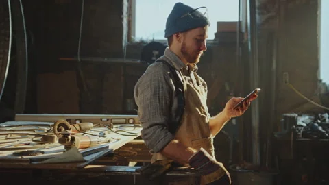Blacksmith Using Smartphone during Break in the Workshop Stock Footage 274391908