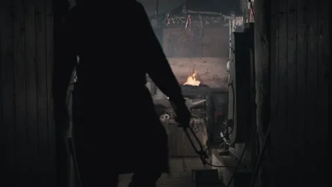 Blacksmith walks into his workshop starts forging iron making a knife Stock Footage 131758322