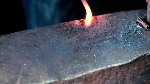Blacksmith work. Blacksmith beats a piece of white hot metal with a hammer on an Stock Footage 76373387
