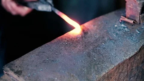 Blacksmith work. Blacksmith beats a piece of white hot metal with a hammer on an Stock Footage 76373442