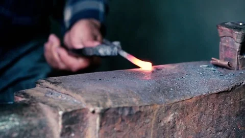 Blacksmith work. Blacksmith beats a piece of white hot metal with a hammer on an Stock Footage 76373525