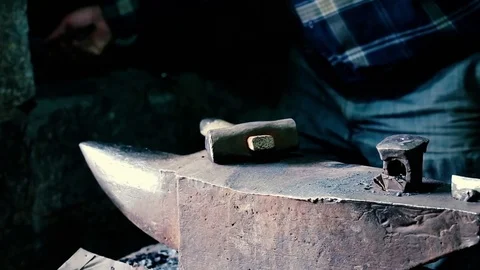 Blacksmith work. Blacksmith beats a piece of white hot metal with a hammer on an Stock Footage 76373561