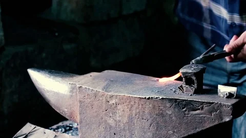 Blacksmith work. Blacksmith beats a piece of white hot metal with a hammer on an Stock Footage 76373587