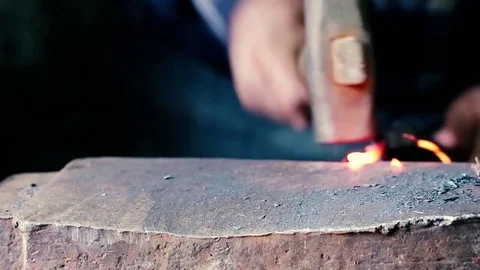 Blacksmith work. Blacksmith beats a piece of white hot metal with a hammer on an Stock Footage 76373596