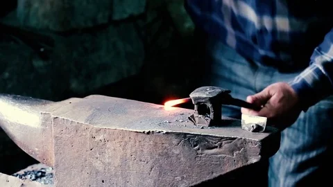 Blacksmith work. Blacksmith beats a piece of white hot metal with a hammer on an Stock Footage 76373630
