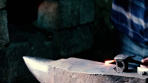 Blacksmith work. Blacksmith beats a piece of white hot metal with a hammer on an Stock Footage 76373637