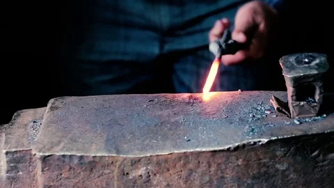 Blacksmith work. Blacksmith beats a piece of white hot metal with a hammer on an Stock Footage 76373661