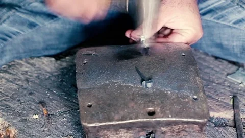 Blacksmith work. Blacksmith beats a piece of white hot metal with a hammer on an Stock Footage 76373743
