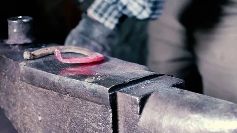 Blacksmith work. Blacksmith beats a piece of white hot metal with a hammer on an Stock Footage 76373786