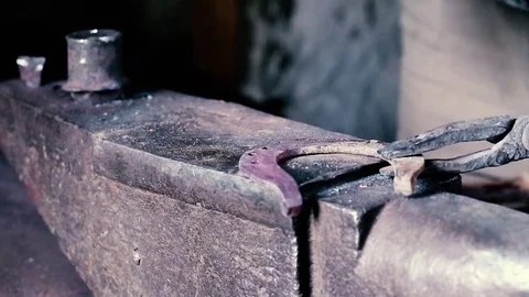 Blacksmith work. Blacksmith beats a piece of white hot metal with a hammer on an Stock Footage 76373796