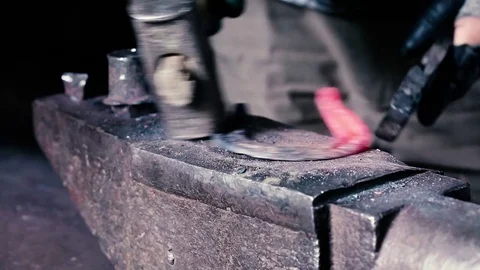 Blacksmith work. Blacksmith beats a piece of white hot metal with a hammer on an Stock Footage 76373818