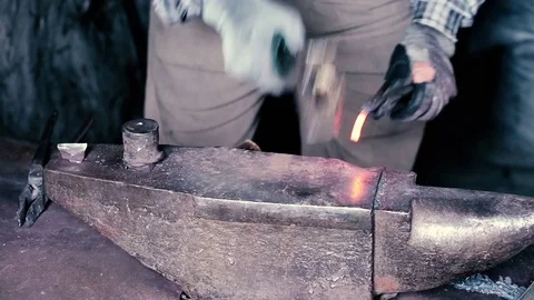 Blacksmith work. Blacksmith beats a piece of white hot metal with a hammer on an Stock Footage 76373853