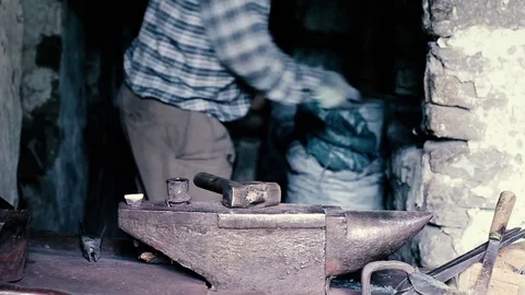 Blacksmith work. Blacksmith beats a piece of white hot metal with a hammer on an Stock Footage 76373891