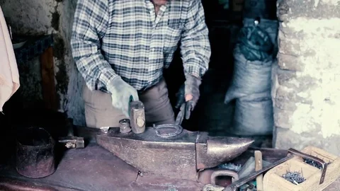 Blacksmith work. Blacksmith beats a piece of white hot metal with a hammer on an Stock Footage 76373920