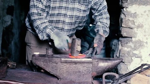 Blacksmith work. Blacksmith beats a piece of white hot metal with a hammer on an Stock Footage 76373992