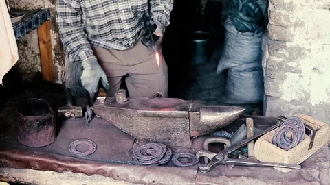 Blacksmith work. Blacksmith beats a piece of white hot metal with a hammer on an Stock Footage 76374052