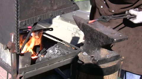 Blacksmith work close up, bending hot metal bar, two takes. Stockbeeldmateriaal 342242356
