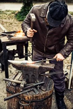 Blacksmith working with hammer. Red hot iron. Stock Photos