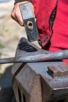 A blacksmith working a piece of iron while working on an anvil Stock Photos