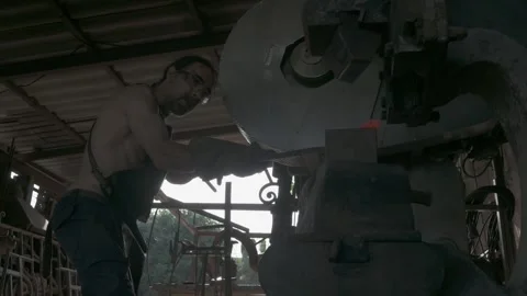 Blacksmith working a piece of steel on a mechanical hammer. Stock Footage 248959157