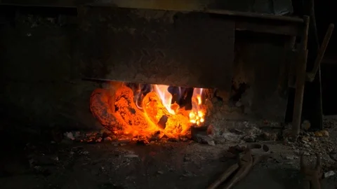 Blacksmith working in a smithery. heating glowing red metal in an oven Stock Footage 71391658