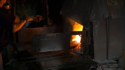 Blacksmith working in a smithery putting charcoal in a furnace oven Stock Footage 71391173