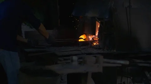 Blacksmith working in a smithery putting charcoal in a furnace oven Stock Footage 71391499